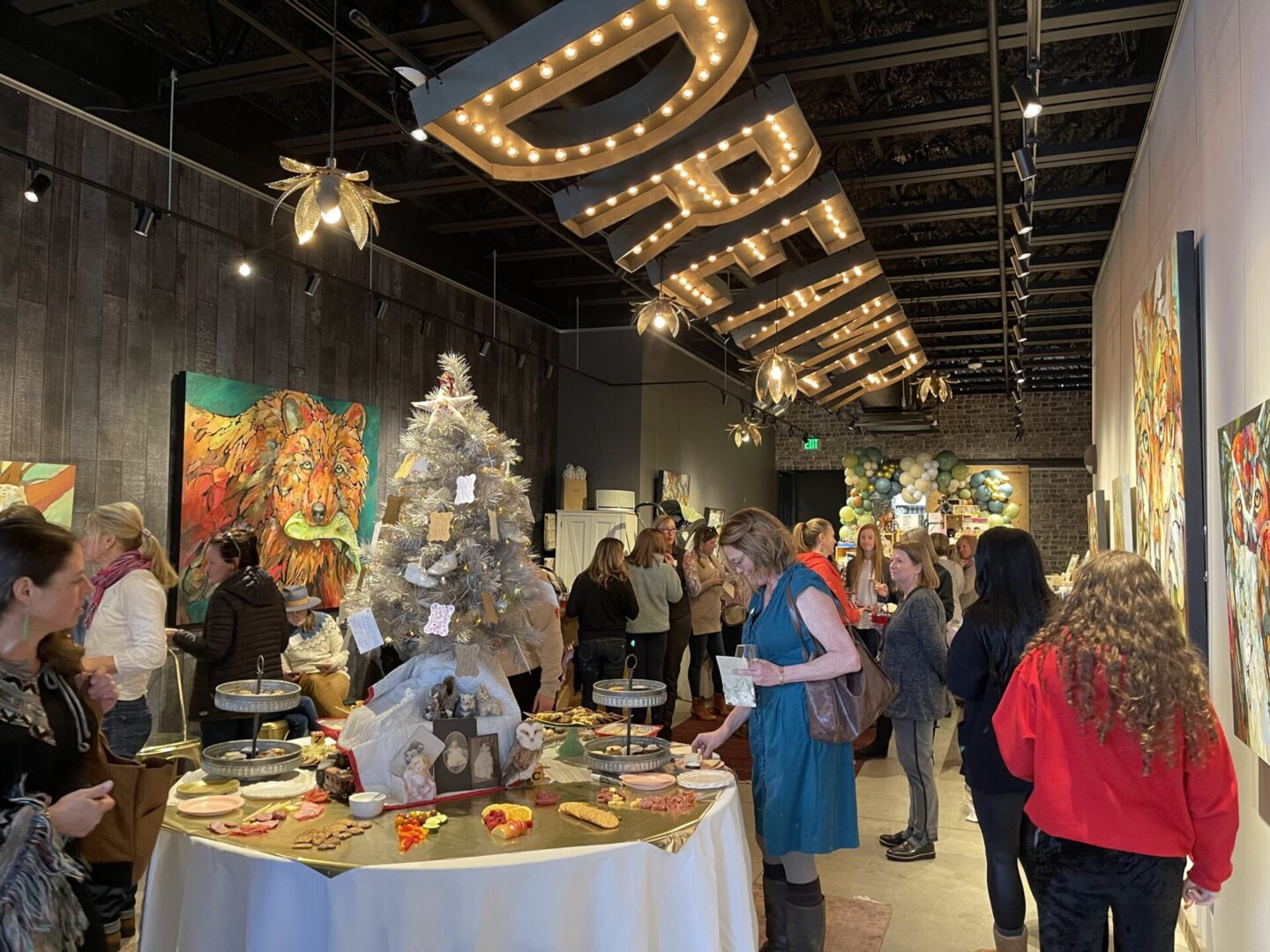 Crowded gallery event with artwork and refreshments